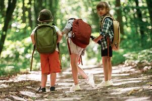 Two ,girls and a boy. Kids in forest ,at summer daytime together photo