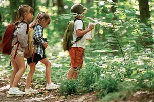 Two girls ,and ,a boy. Kids in forest at summer daytime together photo