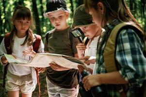 Looking at the, map. Kids in forest at ,summer daytime together photo