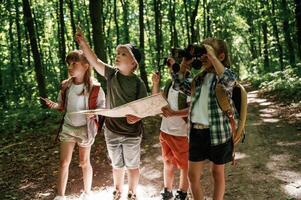 Paper traditional map. Kids in forest at summer daytime together photo