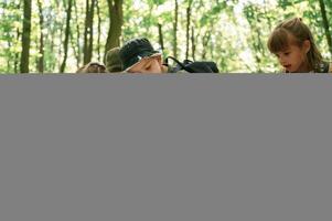 On the ground with map. Kids in forest at summer daytime together photo