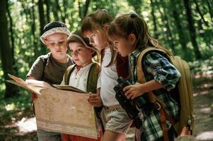Paper map ,in ,hands. Kids in forest at summer daytime together photo