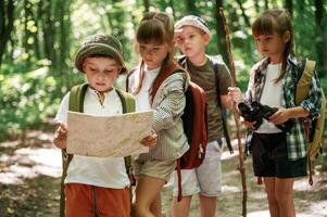 Smart ,boy is reading the map.. Kids in forest at summer daytime together photo