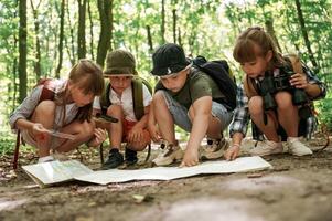On the ground, with map. Kids in forest at summer daytime together photo