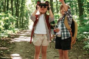 Using ,binoculars.. Kids in forest at summer daytime together photo