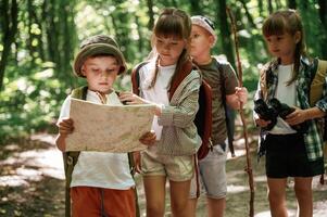 Smart ,boy is reading the map. Kids in forest at summer daytime together photo