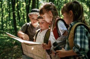 Paper map, in, hands. Kids in forest at summer daytime together photo