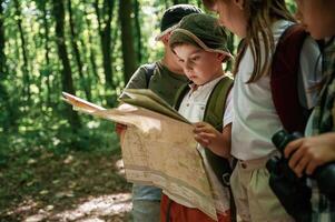 Paper map, in hands. Kids in forest at summer daytime together photo