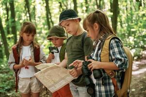 Paper ,traditional map. Kids in forest at summer daytime together photo