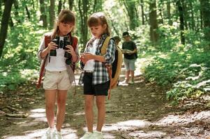 Using, binoculars. Kids in forest at summer daytime together photo