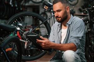 Using digital tablet. Repair man in bicycle shop, working in store.. photo