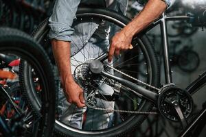 Close up view of man's hands that is repairing bicycle. photo