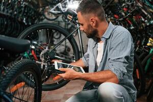 Using ,digital ,tablet. Repair, man in bicycle shop, working in store photo