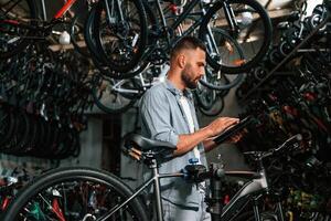 Using, digital tablet. Repair man in bicycle shop, working in store photo