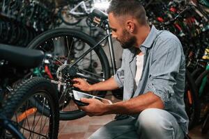 Using digital tablet. Repair man ,,,in bicycle ,shop, working in store photo