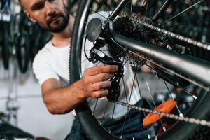 Derailleur, adjustment... Repair man in bicycle shop, working in store photo