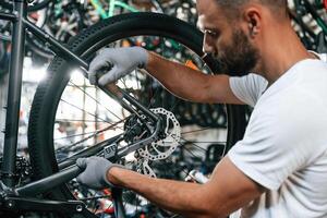 Employee is busy. Repair man in bicycle shop, working in store photo