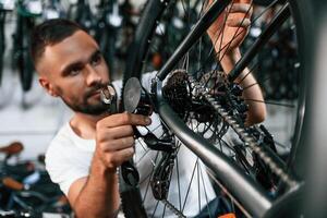 Checking the wheel and brake system. Repair man in bicycle shop, working in store photo