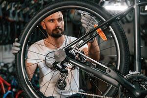 Spokes, replacement... Repair man in bicycle shop, working in store photo