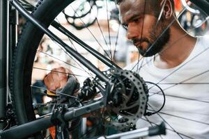 Cleaning the chain. Repair man, in, bicycle, shop, working in store photo