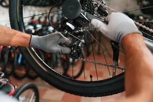 Fixing the derailleur. Close up view of man's,,, hands that is repairing bicycle photo