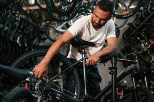 Adjusting ,the wheel. Repair man in bicycle ,,shop, working in store photo