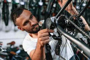 Checking the wheel and brake system., Repair man in bicycle shop, working in store photo