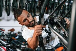 Checking the wheel and brake ,system. Repair man in bicycle shop, working in store photo