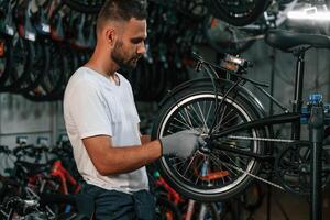 Indoors,, many bikes. Repair man in bicycle shop, working in store photo
