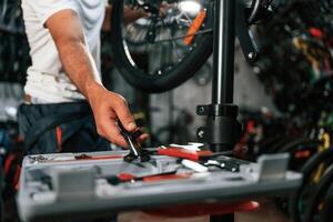 Taking ,wrench. Close up view of man's hands that is repairing bicycle photo