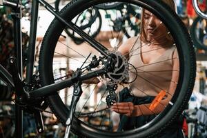Back wheel, taking ,care ,,of it. Repair woman in bicycle shop, working in store photo