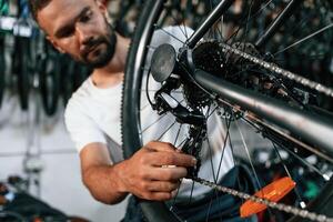 Derailleur adjustment. Repair man ,in bicycle shop, working in store photo