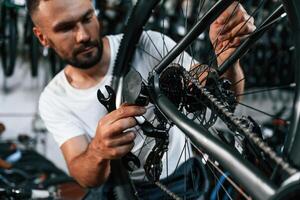 Checking, the ,wheel and brake system. Repair man in bicycle shop, working in store photo