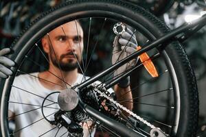 Spokes replacement. .Repair man in bicycle shop, working in store photo