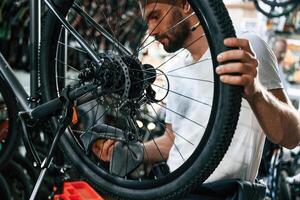 Cleaning ,the chain. Repair man in bicycle shop, working in store photo