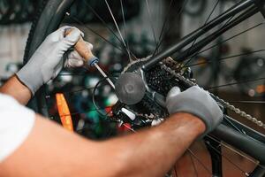 Fixing the derailleur. .Close up view of man's hands that is repairing bicycle photo