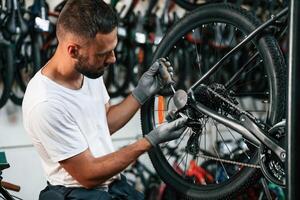 Spokes replacement.. Repair man in bicycle shop, working in store photo