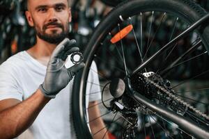 Holding ,circle shaped part near the wheel. Repair man in bicycle shop, working in store photo