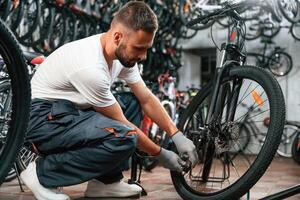 Inflates, a, tire ,with hand pump. Repair man in bicycle shop, working in store photo