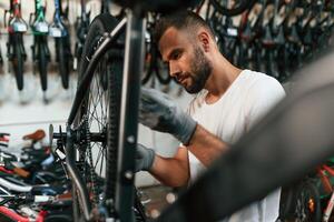 In ,,grey colored gloves. Repair man in bicycle shop, working in store photo