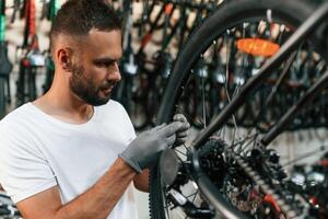 In, grey colored gloves. Repair man in bicycle shop, working in store photo