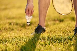 Close up view of man that is taking shuttlecock from ,,the ,,ground photo
