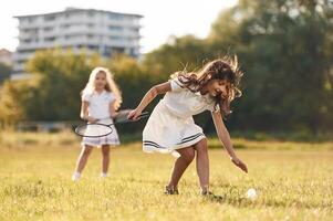Girls are playing badminton. Happy ,,,kids ,are ,on the summer field photo