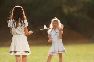 Girls are playing badminton... Happy,, kids are on the summer field photo