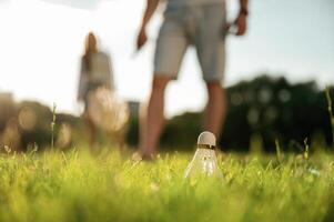 Guy is picking ,,up, the ,shuttlecock. Man with woman are playing badminton on the field photo
