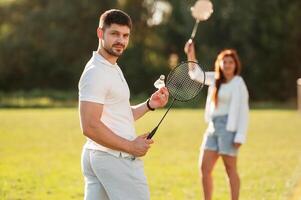 Weekend ,activities., Man with woman, are playing badminton on the field photo