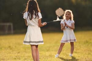Girls ,are, playing,, badminton. Happy kids are on the summer field photo