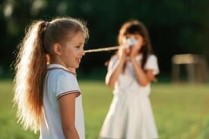 Using tin ,can,, telephone. Happy kids are on ,the summer field photo