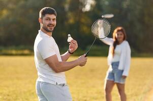 Weekend activities. Man with woman ,are, playing badminton on the field photo