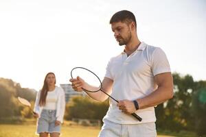 Man ,with ,woman ,are playing badminton on the field photo